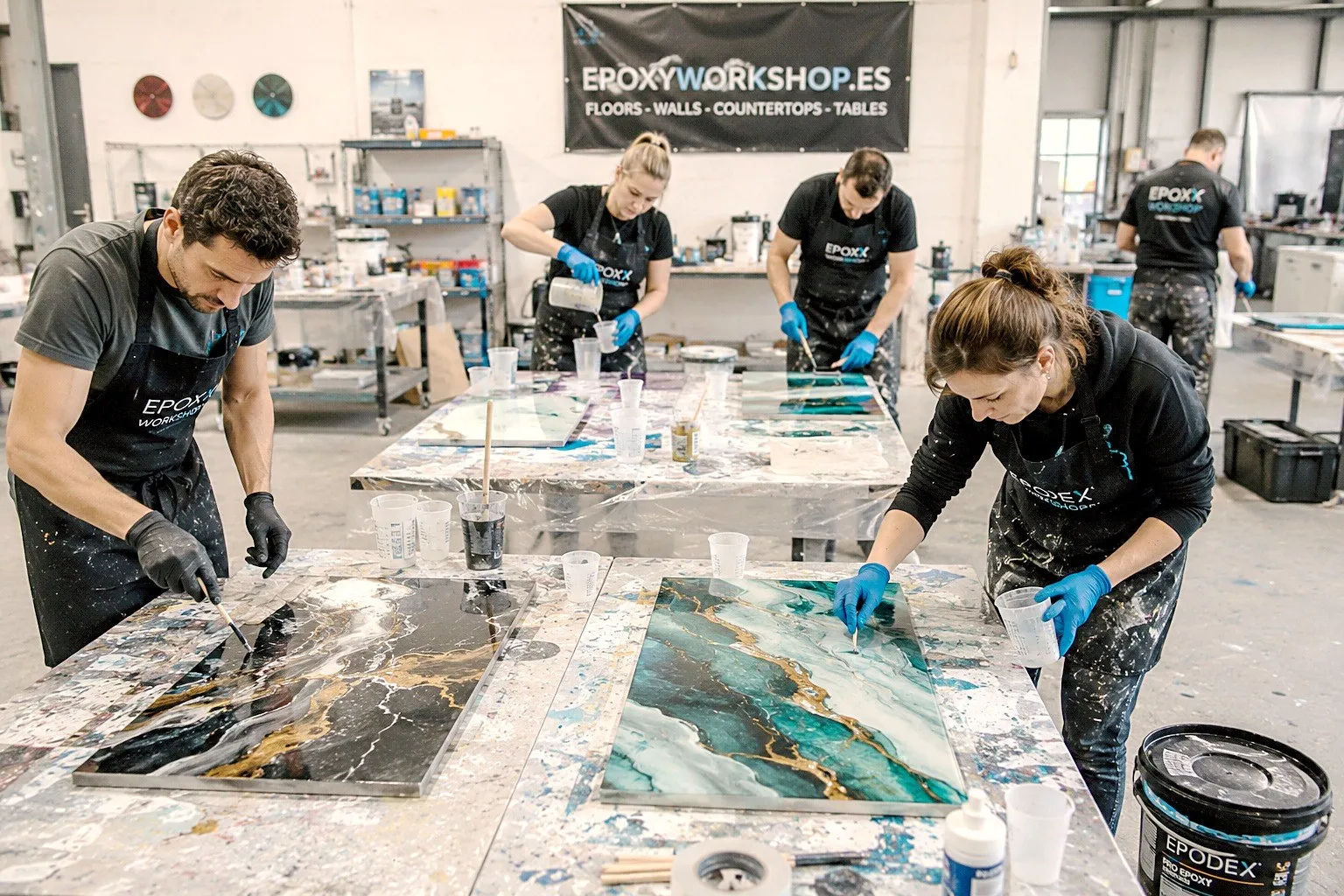 Participants working on large epoxy panels with a marble look in black, gold and turquoise in the Epoxyworkshop.es studio